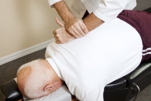 Closeup of chiropractors hands doing spinal adjustment on senior man