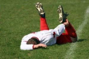 soccer playing laying on ground with sports injury