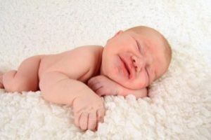 newborn baby boy frowning with colic.